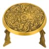 A large, traditional brass mukkali stool with three sturdy legs and an intricately designed seat, shining with a polished golden hue.